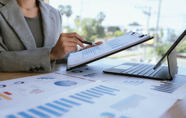 Businesswoman analyzing financial charts and data reports with a laptop at the office, planning strategy and performance review.