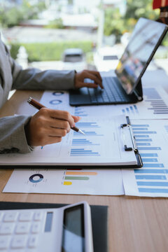 Businesswoman analyzing financial charts and data reports with a laptop at the office, planning strategy and performance review.
