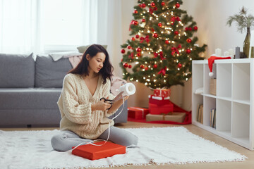 Woman Preparing Christmas Gift with Ribbon in Festive Home