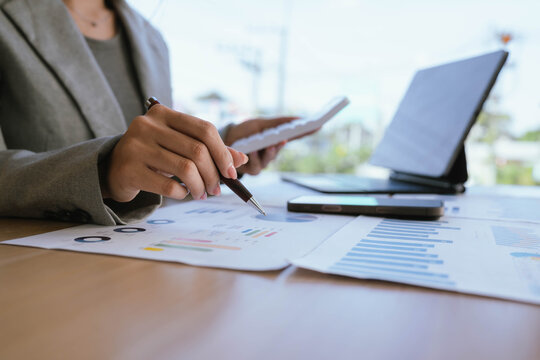 Businesswoman analyzing financial charts and data reports with a laptop at the office, planning strategy and performance review.