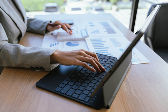 Businesswoman analyzing financial charts and data reports with a laptop at the office, planning strategy and performance review.