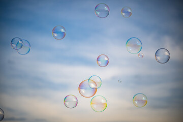 Soap Bubbles Drifting Through Air with Soft Cloud Background