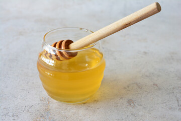 Golden Honey Jar with Wooden Dipper on marble background