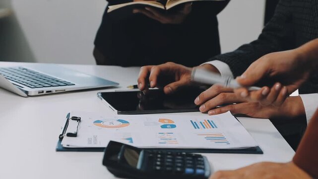 Financial analysts analyze business financial reports on a digital tablet planning investment project during a discussion at a meeting of corporate showing the results of their successful teamwork. - Powered by Adobe