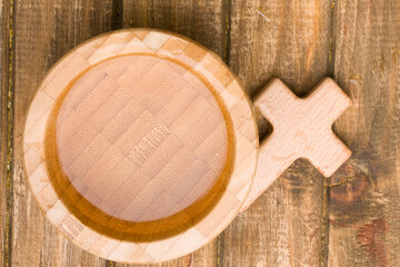 Holy water and a cross on a wooden background