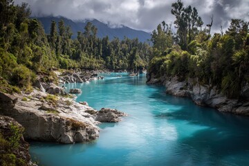 Stunning Hokitika Gorge Landscape: A Blue River Surrounded by Lush Nature and Dramatic Clouds in New Zealand's Scenic Park