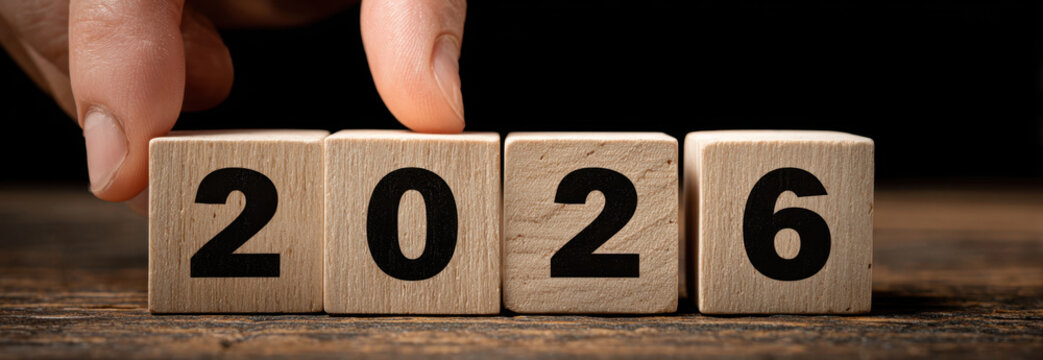 Businessman hand placing wooden blocks to form year 2026, symbolizing planning and future goals. image conveys sense of anticipation and preparation for upcoming opportunities