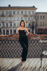 Elegant woman in black full-length on city balcony