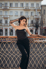 Glamorous woman in black with gloves posing on balcony