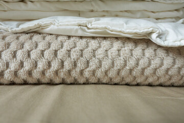 Warm beige blankets on the table, close-up view. A stack of beige linen, close-up.