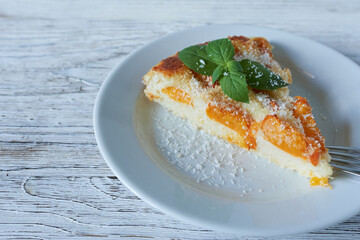 Cottage cheese casserole with peaches and mint on wooden background