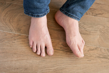 Close-up of a man's bare feet on a wooden floor.