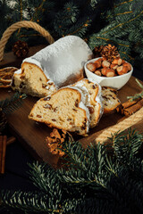 Christmas stollen on a wooden board with green branches of a Christmas tree. Christmas background, Christmas desserts