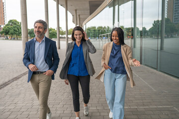Obraz premium Diverse business team walking, talking, and smiling outdoors