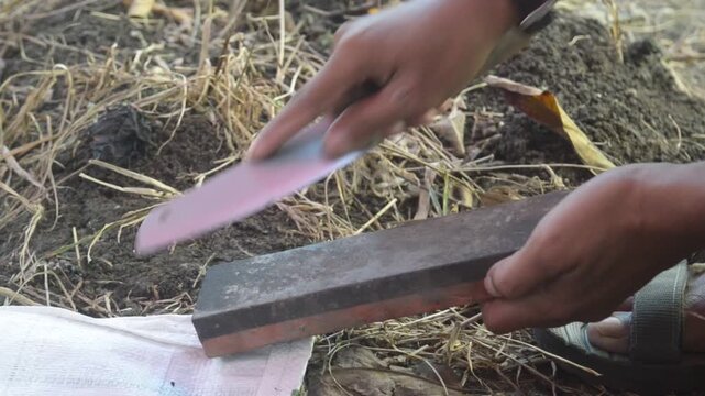Sharpening a knife on a sharpening stone outdoors
