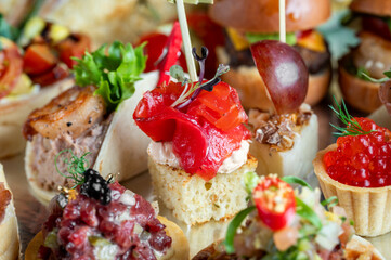 A close-up shot of a variety of colorful, gourmet canapés and finger foods arranged on a table, ready for a catering event or party