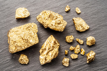 Gold nuggets on black stone background top view. Imitation of gold nuggets.