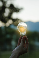 A hand holding a glowing light bulb against a dark background, symbolizing creativity, innovation, and new ideas.