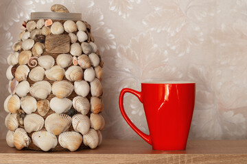 Orange mug and handmade vase in the apartment interior.