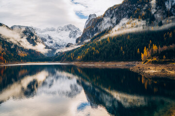 Obraz premium Beautiful mountain landscape with clear lake Gosau reflecting trees and clouds in autumn