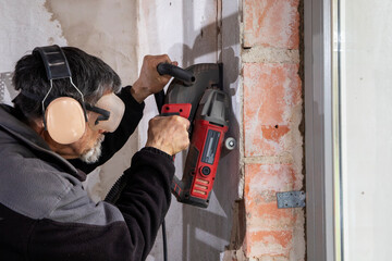 Construction Worker using a Wall Chaser to make Channels for Electric Installation