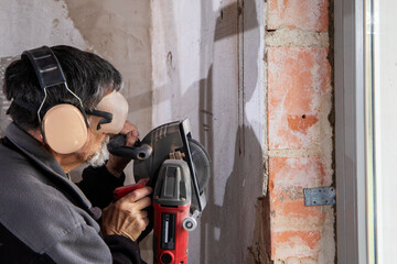 Construction Worker using a Wall Chaser to make Channels for Electric Installation