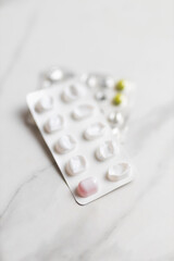 Medication blister packs on marble surface with white and pink capsules