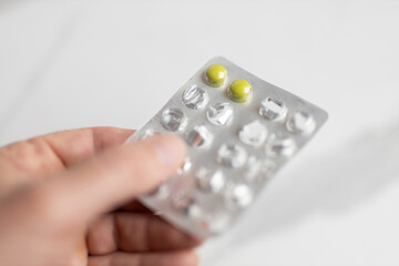 Close-up of hand holding blister pack with two yellow pills