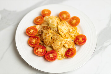 Delicious pasta with grilled chicken and cherry tomato garnish on white plate