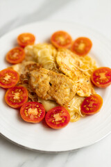 Delicious chicken and cheese pasta with fresh cherry tomatoes on white plate