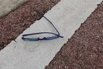 Broken blue eyeglasses on the road