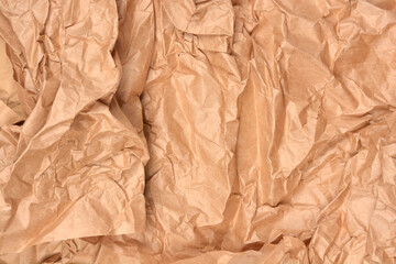 A full-frame close-up of a textured surface composed of crumpled and wrinkled brown kraft paper, perfect for an organic or recycling themed background
