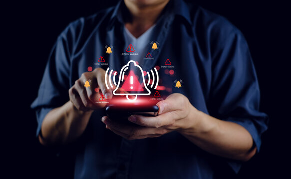 System warning alert cybersecurity risk on virtual interface, man using smartphone receives digital notification about security breach, data protection, and online threat prevention in dark background