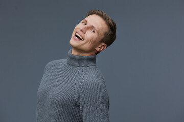 Smiling young caucasian man wearing gray turtleneck sweater posing on plain dark gray background emotional joyful happy digital detox concept