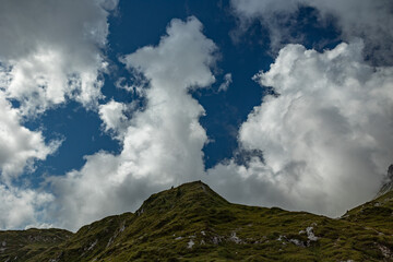 cresta erbosa di una montagna nel nord Italia, di giorno, sotto un cielo parzialmente nuvoloso, in autunno