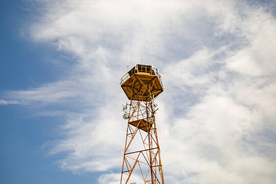 Metal watchtower platform against blue sky with clouds and rust