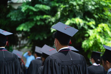 A group of graduates are standing in a field wearing black gowns and caps