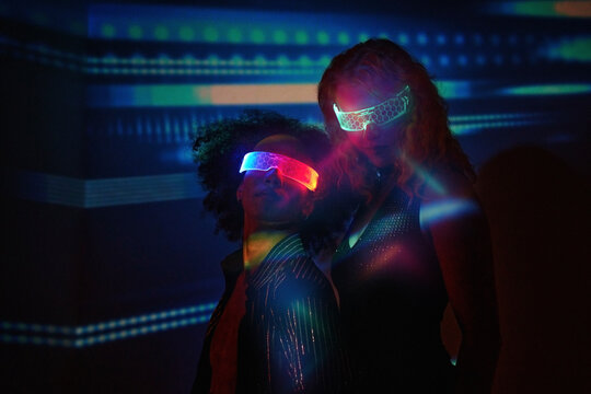 Two people dancing in nightclub with VR glasses and colorful lights