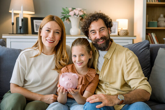 Family smiling together saving money with a piggy bank on the couch