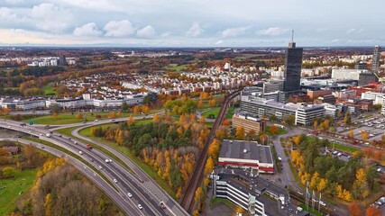 Aerial view of Kista Science Tower in autumn surrounded by colorful trees and roads with moving cars, Stockholm, Stockholm County, Sweden.