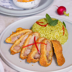 Delectable and appetizing fried pork chop with vibrant green rice on a plate