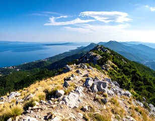 Sunny mountain ridge with ocean vista, under a partly cloudy sky