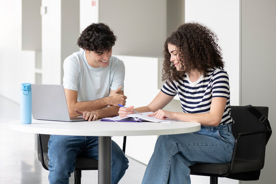 Happy student explaining friend at round table in university