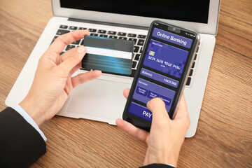 Man with credit card using smartphone for online payment at table, closeup