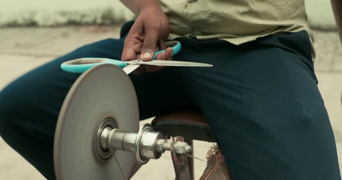 A worker giving the edge to a knife using a grinding wheel