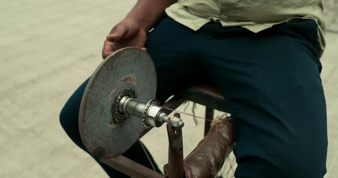 A worker giving the edge to a knife using a grinding wheel