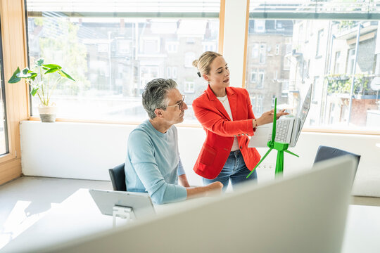 Businesswoman discussing over laptop with colleague in office