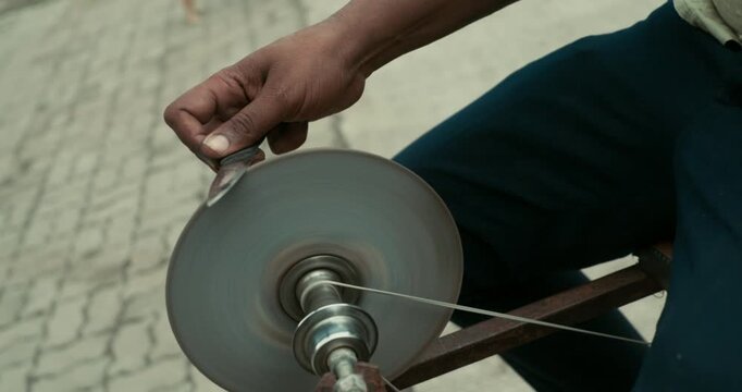 A worker giving the edge to a knife using a grinding wheel