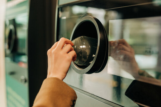 Hand returning plastic bottle in reverse vending machine for recycling