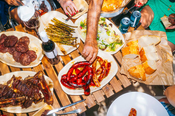 Outdoor meal with grilled meats, vegetables, and bread.